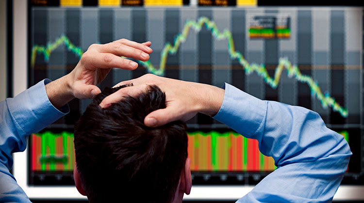 Banker vor dem Monitor sieht fallende Aktienkurse an den Börsen