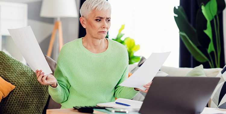 Frau checkt am Laptop Papiere und Dokumente