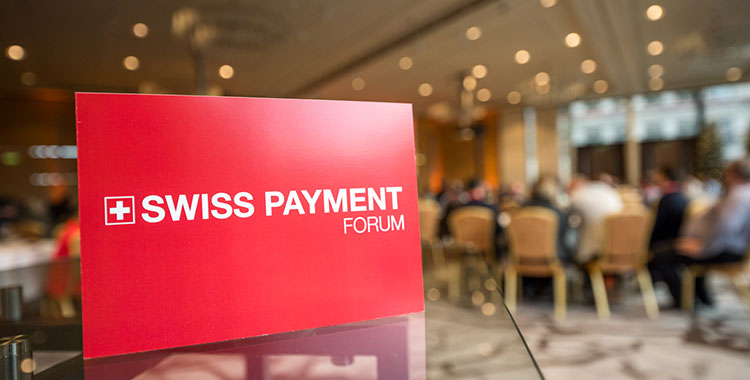 Plakat Swiss Payment Forum, im Hintergrund Tagungsteilnehmer