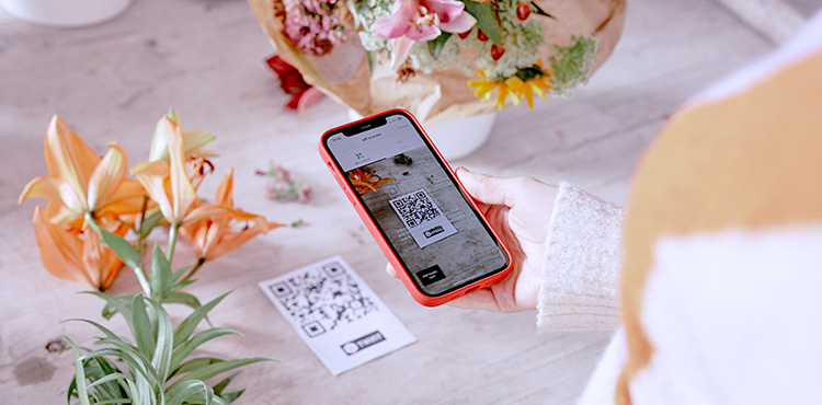 Frau mit Smartphone bezahlt über Twint auf dem Handy ihre gekauften Blumen
