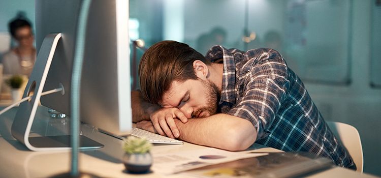 Ein schlafender Mitarbeiter am PC zeigt AI-Fatigue
