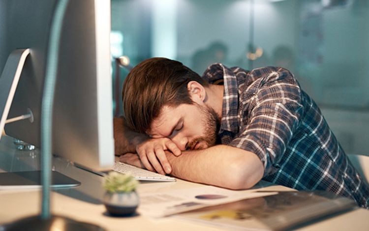 Ein schlafender Mitarbeiter am PC zeigt AI-Fatigue