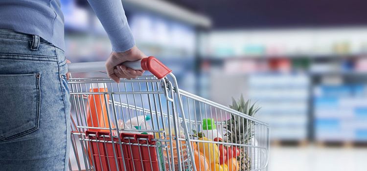 Eine Frau füllt im Supermarkt ihren Einkaufswagen