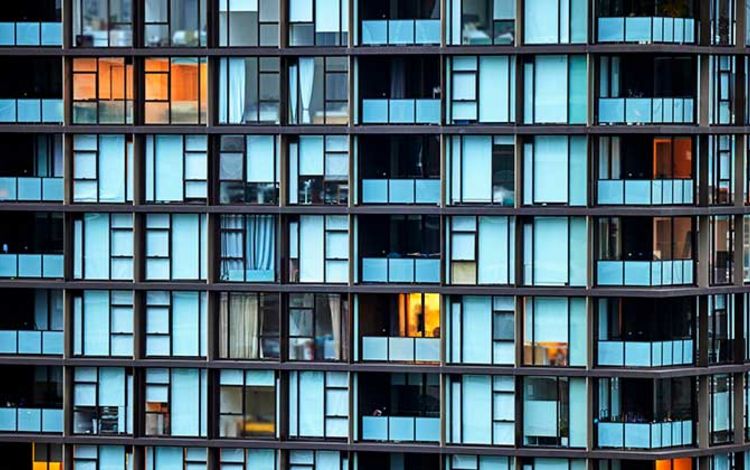 Fassade eines Wohnblocks mit teilweise erleuchteten Fenstern