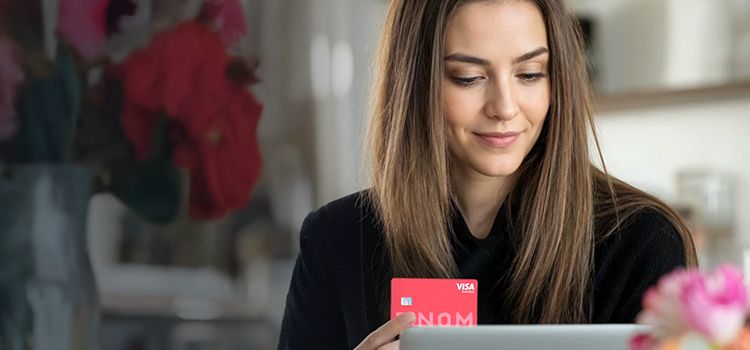 Junge Unternehmerein am Laptop mit Kreditkarte in der Hand