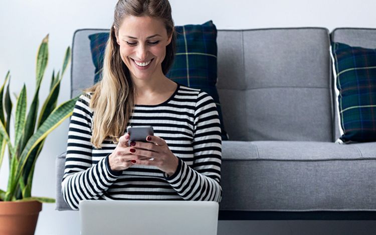 Junge Frau zu Hause am Smartphone und Laptop
