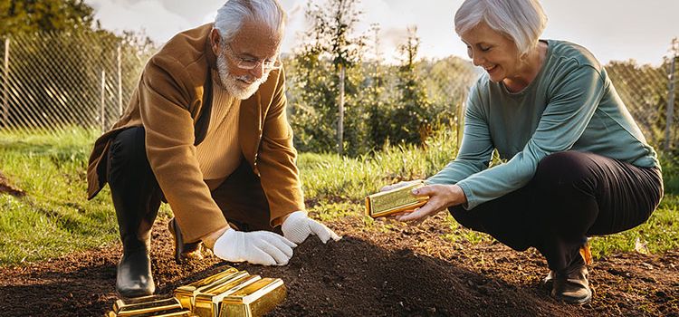 Ein älteres Paar vergräbt Goldbarren im Garten