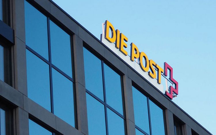 Hauptgebäude der Post mit Logo gegen blauen Himmel